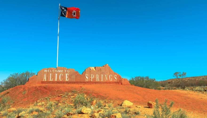 Welkomstbord van Alice Springs en Australische vlag van Northern Territory in Centraal Australië